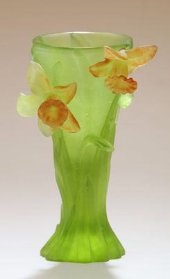 un vase vert contenant des fleurs, posé sur une surface blanche