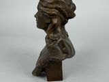 a bronze bust of a woman with a hat on her head