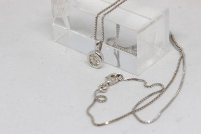 a clear box with a silver necklace and a silver chain