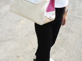 a woman talking on a cell phone while holding a white purse
