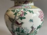 a white and green vase with a bird and flowers on it