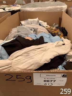 a cardboard box filled with clothes and a pile of clothes