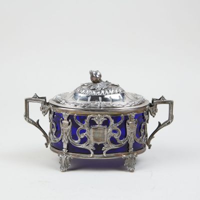 an antique silver and blue glass covered dish with a bird on top