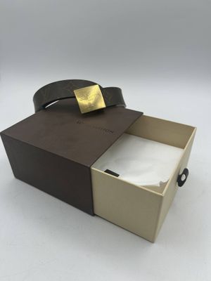 une boîte ouverte sur laquelle est posée une ceinture en cuir