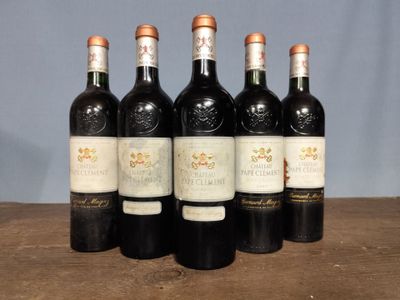 six bottles of wine are lined up on a wooden table