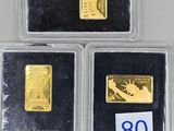 three gold bars are in plastic cases on a table