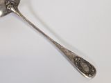 an antique spoon with a silver handle on a white surface