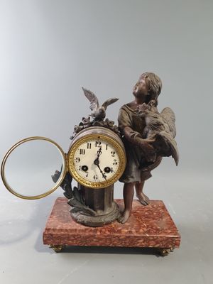 une statue représentant un homme tenant une horloge sur laquelle est posé un oiseau