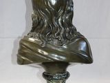 bronze bust of a man with long hair on a marble base