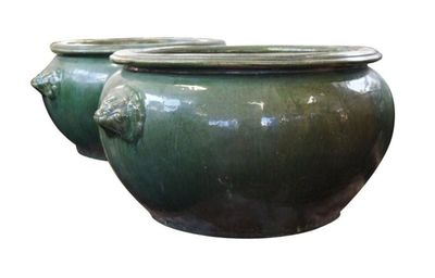 deux vases verts posés l'un à côté de l'autre sur une surface blanche