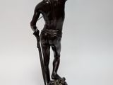 an antique bronze statue of a man holding a sword and a shield