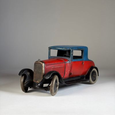 une petite voiture rouge avec un toit bleu posée sur une surface blanche