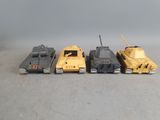 four toy tanks are lined up in a row on a gray surface