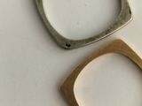 two pieces of silver and gold are sitting on a white surface