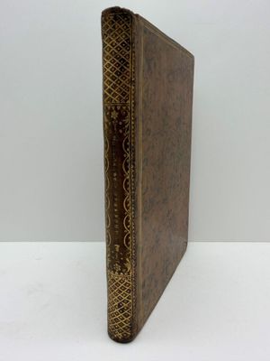 un livre en cuir marron, avec des bordures dorées et un motif décoratif sur la couverture