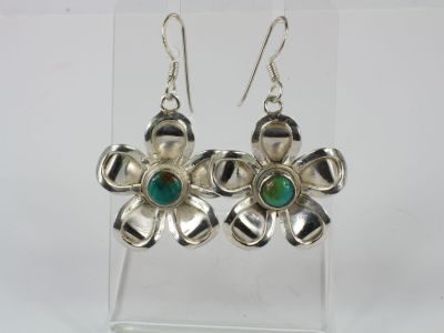 silver flower earrings with green glass beads on a clear acrylic stand