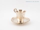 a silver cup and saucer sitting on a saucer