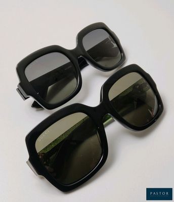 two pairs of black sunglasses sitting on top of a white table