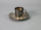 an antique silver cup and saucer on a saucer on a table