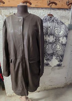 un manteau en cuir marron posé sur un mannequin devant un mur