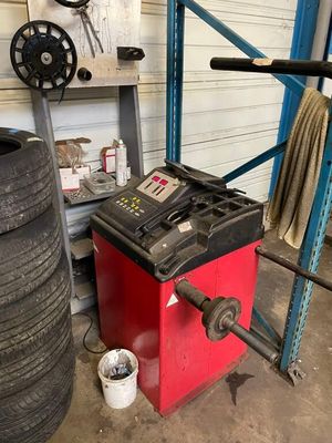 a tire changer in a garage next to a stack of tires