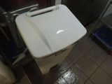 a white trash can sitting in a kitchen next to a refrigerator