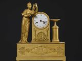 une image représentant une horloge en or et une femme tenant un vase
