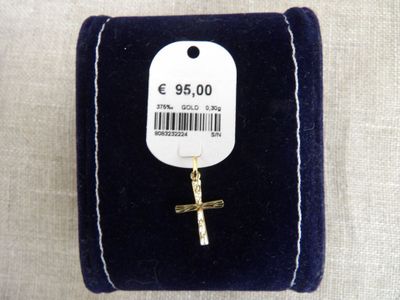 une petite croix en or posée sur un écrin en velours noir