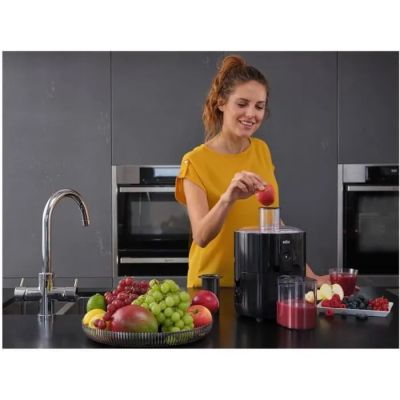 a woman that is making a fruit juice in the kitchen