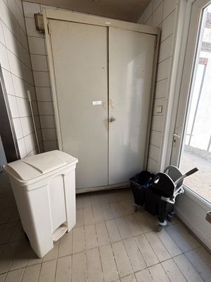 a trash can in the corner of a room next to a window