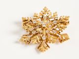 an image of a gold snowflake brooch on a white background