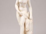 a white marble statue of a woman holding a bag