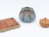 un petit vase et une petite boîte posés sur une surface blanche