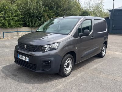 La camionnette grise est garée sur un parking, avec des arbres en arrière-plan.