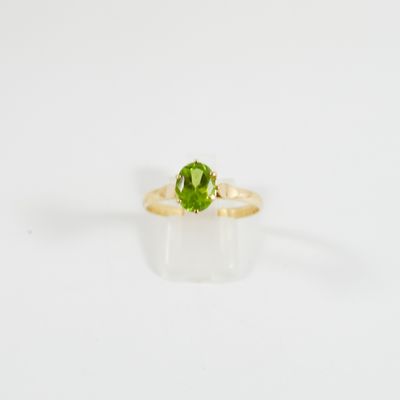 un gros plan d'une bague en tourmaline verte sur une surface blanche