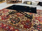 une table basse noire posée sur un tapis dans une pièce
