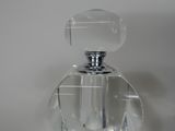 a clear glass bottle with a silver top sitting on a white surface