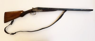 un vieux pistolet avec une crosse en bois et une sangle, posé sur une surface blanche