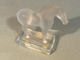 a plastic horse that is standing on a glass block