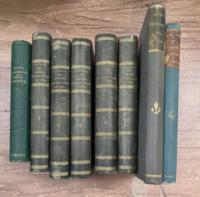 Plusieurs vieux livres sont alignés sur une étagère posée sur un support en bois