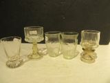 five glasses and a spoon sitting on a table