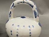 a white tea pot with blue designs on it next to a cup and saucer