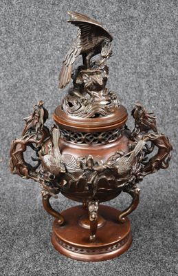 une image représentant un vase en bronze surmonté d'un oiseau