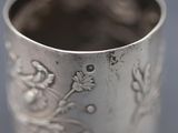 a close up of a silver cup with a flower design on it