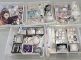 a lot of beads and jewelry in the bins on the table
