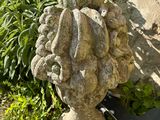 une statue représentant une tête posée sur un rocher, à côté d'un livre