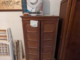une armoire en bois surmontée d'un ventilateur, dans une pièce