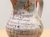 a small white pitcher with blue and orange designs on it