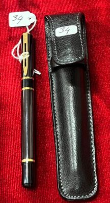 un stylo noir et un étui noir posés sur un tissu rouge