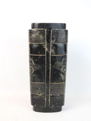 a black vase with a pattern on it sitting on a table